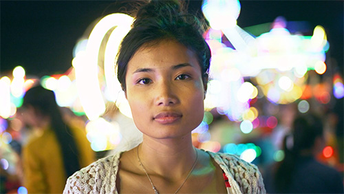 photo of Asian woman with out of focus lights and people in the background